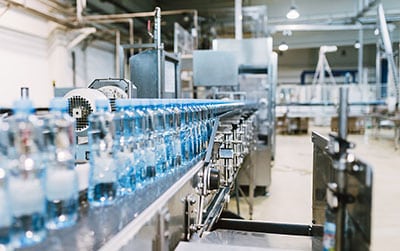 Atelier d'embouteillage où des buses de soufflage Silvent sèchent des bouteilles sur un convoyeur